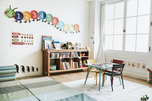 A kindergarten classroom with colorful books, chairs, and decorations.