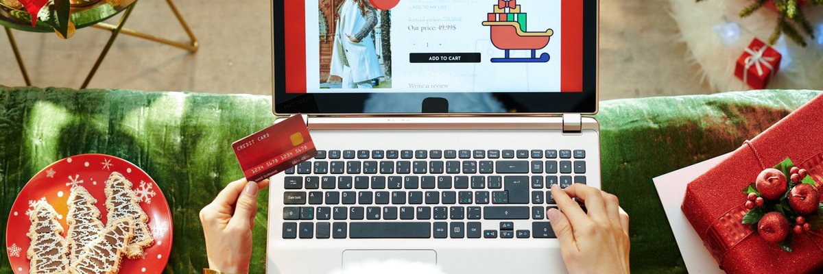 A woman online shopping surrounded by Christmas decorations.