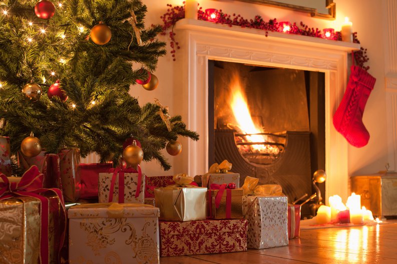 A Christmas tree and lots of presents in front of a fireplace.