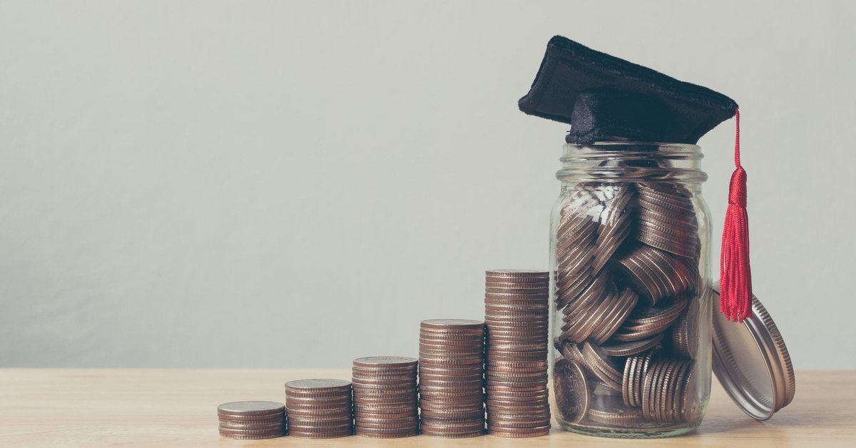 Stacks of coins leading up to a jar of coins with a mortarboard on top