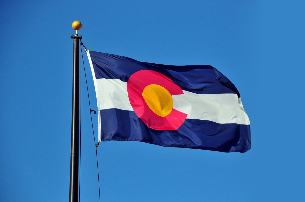 The Colorado state flag fluttering in front of a blue sky.