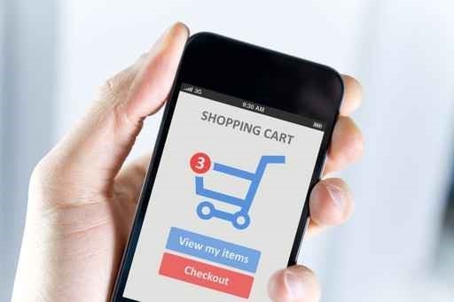 A hand holding a smartphone that show's a shopping cart.
