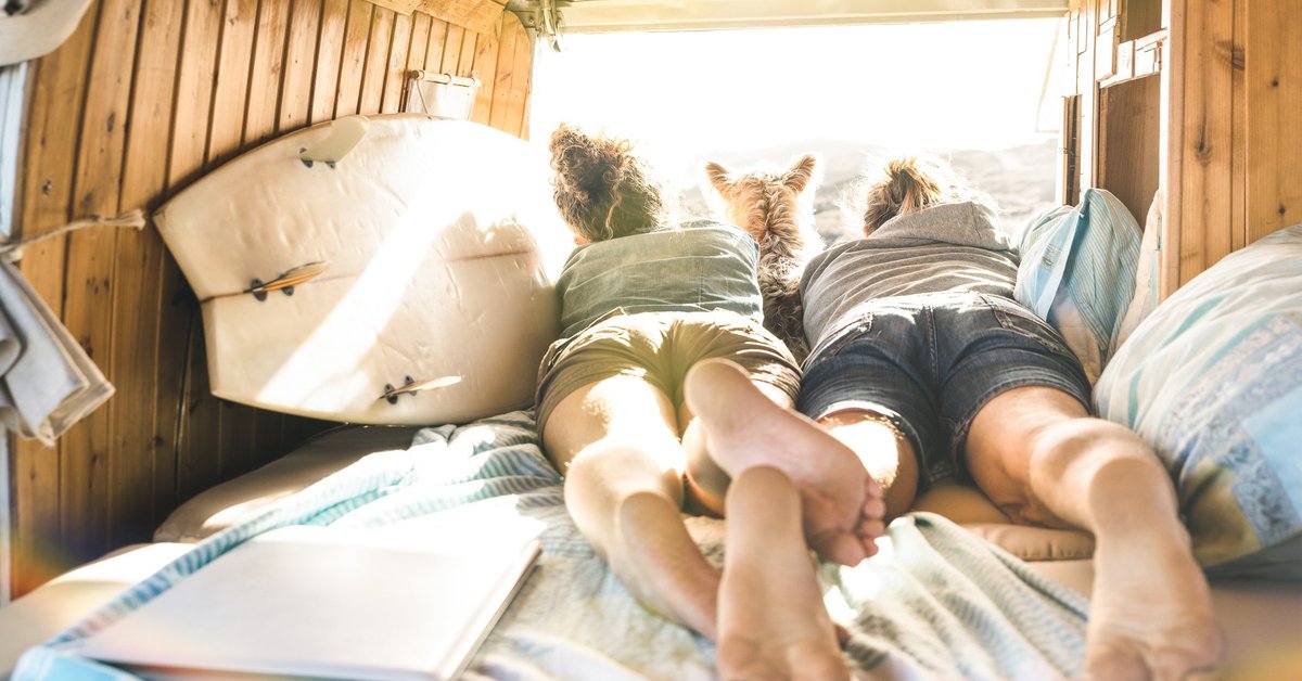 Young couple lying in RV with dog looking out over mountains