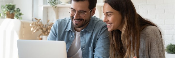 A happy man and woman look at a laptop screen.