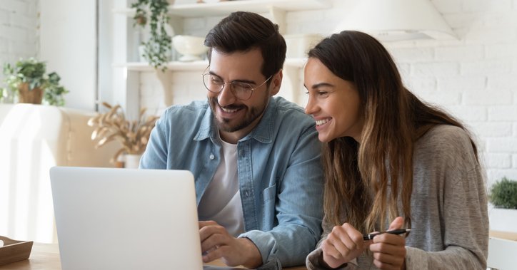A happy man and woman look at a laptop screen.