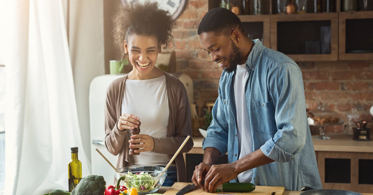 Young smiling couple cooking together at home.