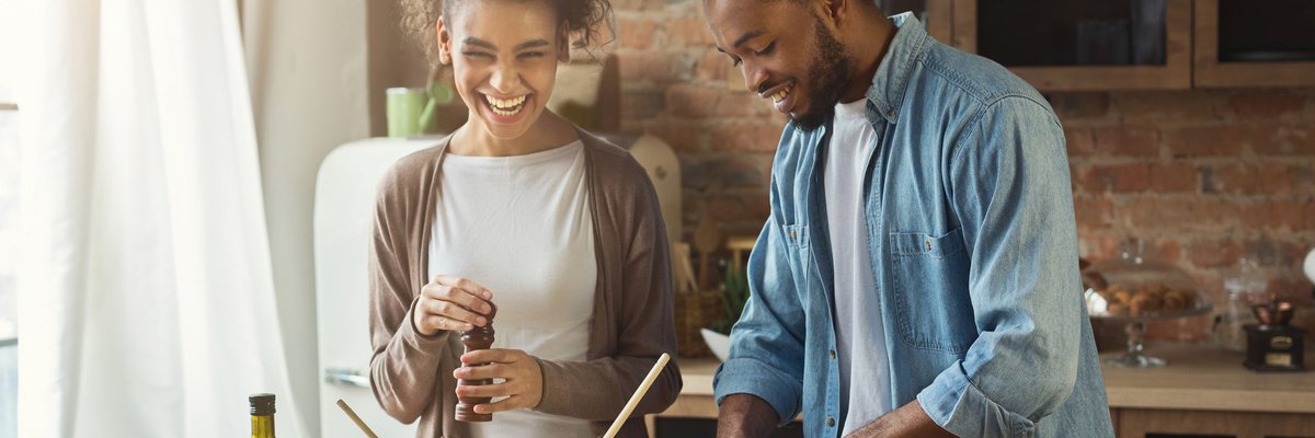 Young smiling couple cooking together at home.
