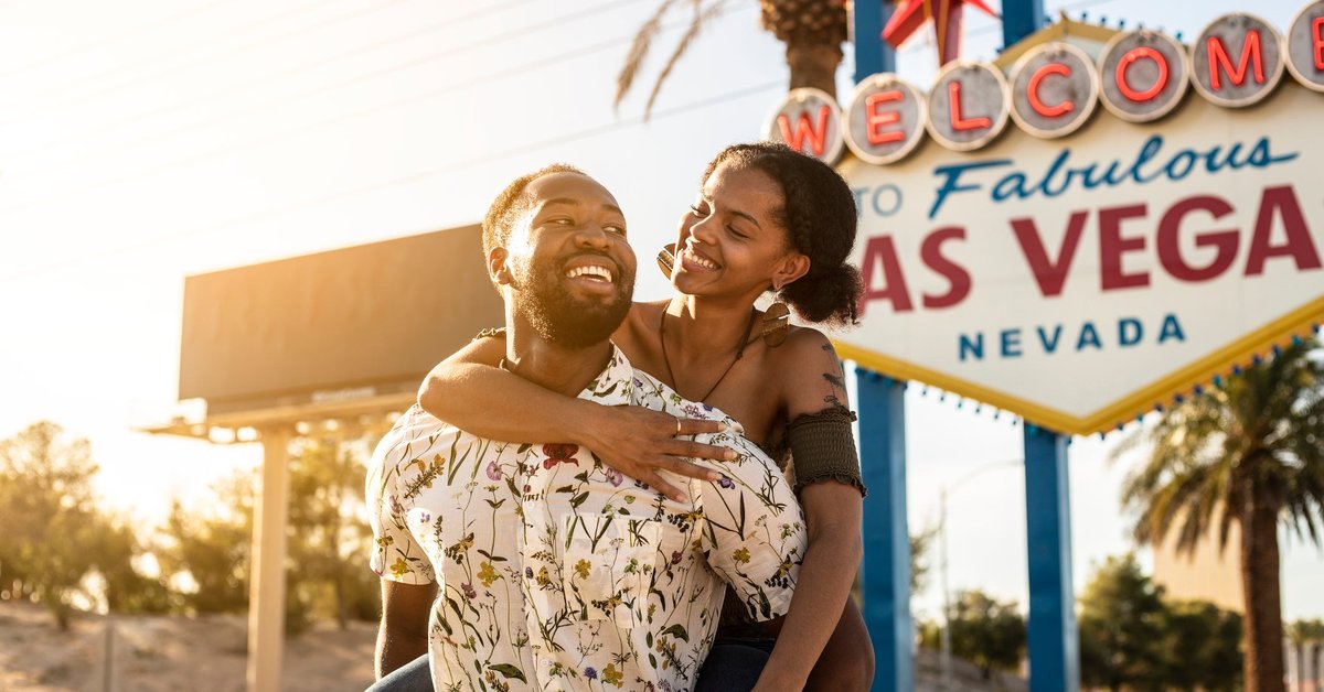 Couple embracing in front of famous Las Vegas sign.