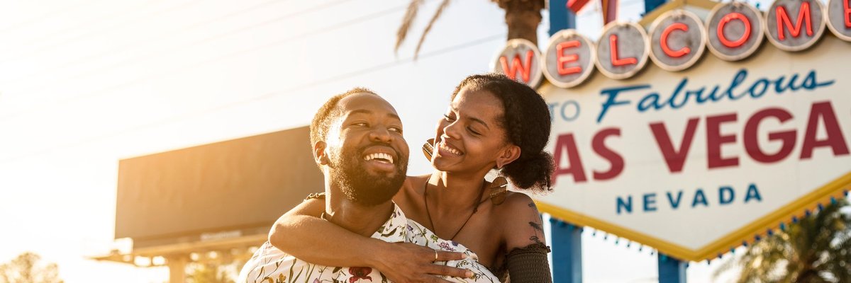 Couple embracing in front of famous Las Vegas sign.