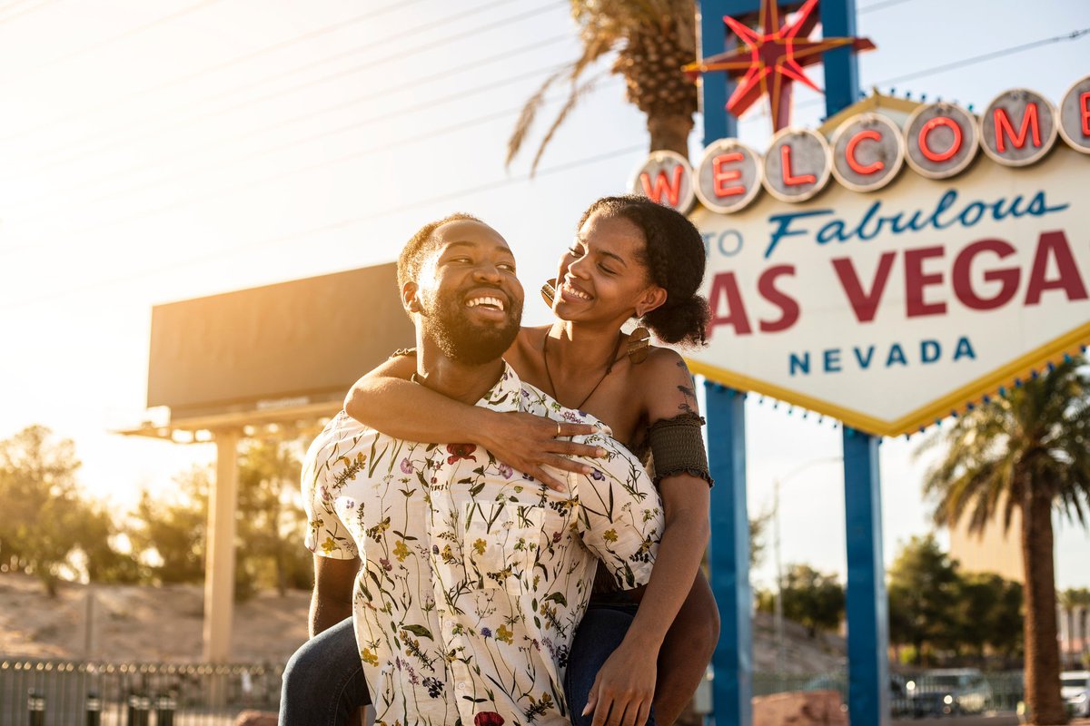 Couple embracing in front of famous Las Vegas sign.