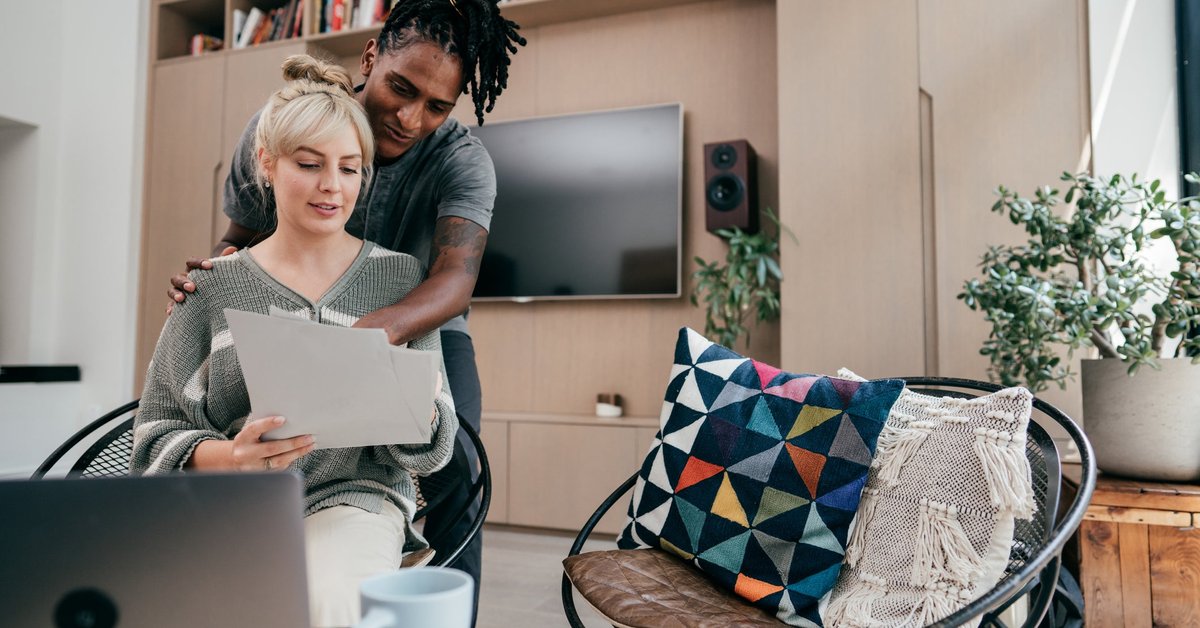 Couple having discussion while using laptop and looking at documents.