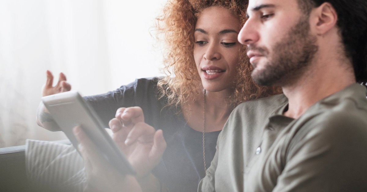 Couple looking at something together on a tablet screen.