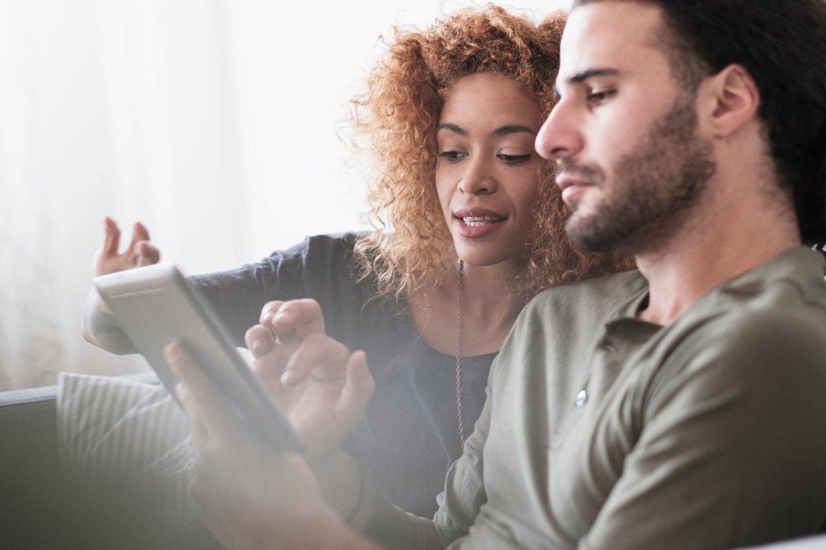 Couple looking at something together on a tablet screen.