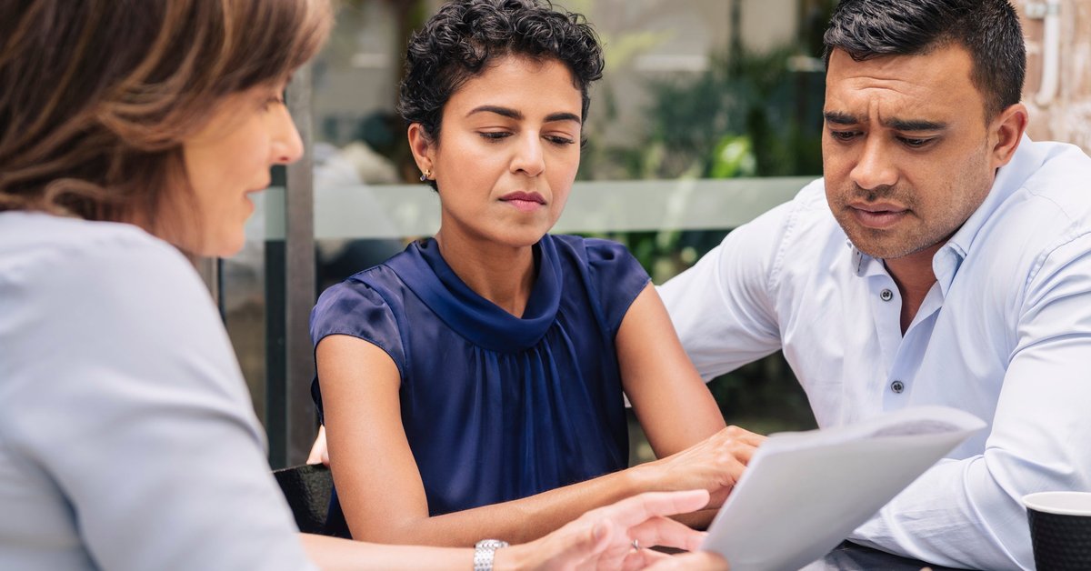 Couple looks displeased by info being shared with them by female professional.