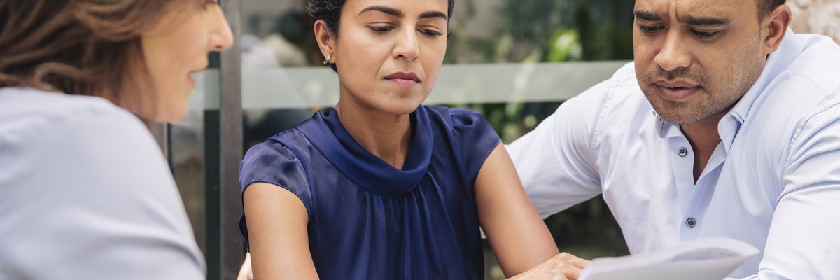 Couple looks displeased by info being shared with them by female professional.