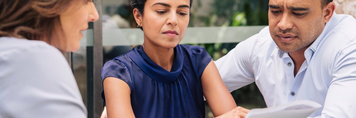 Couple looks displeased by info being shared with them by female professional.