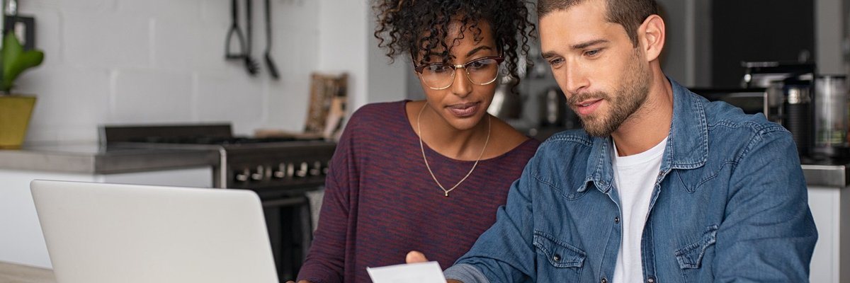 A young couple paying bills at their kitchen table.