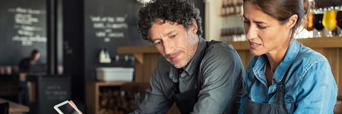 A couple sitting at a table and looking through paperwork together.
