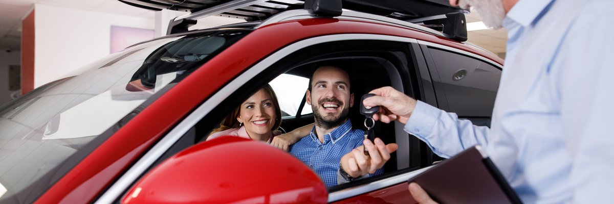 Couple receiving a new car keys from car salesperson.