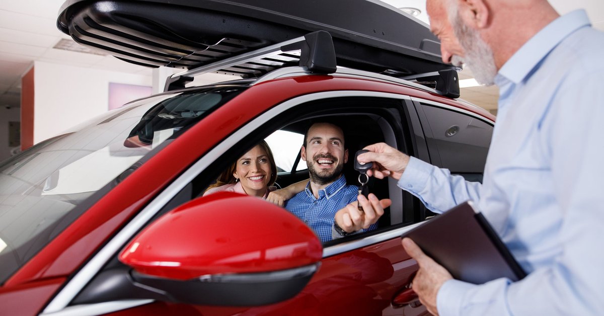 Couple receiving a new car keys from car salesperson.