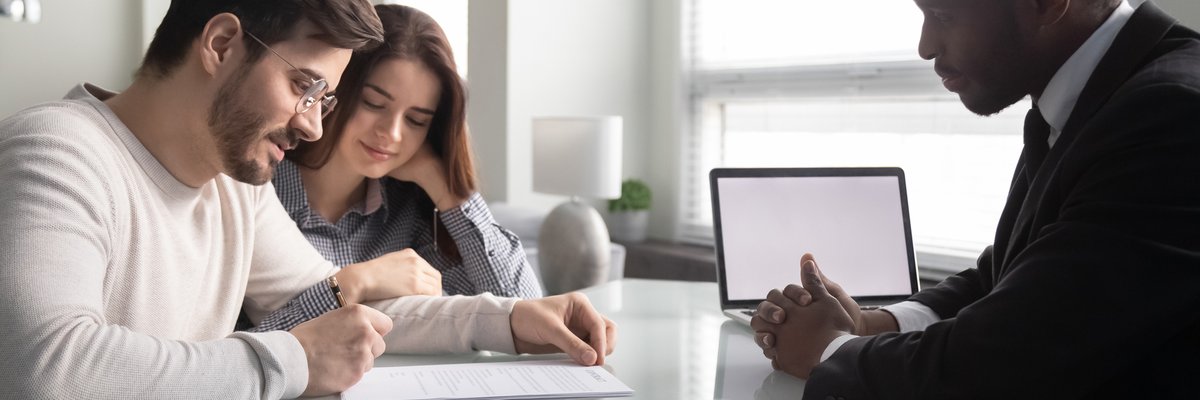 Couple signing paperwork with an agent.