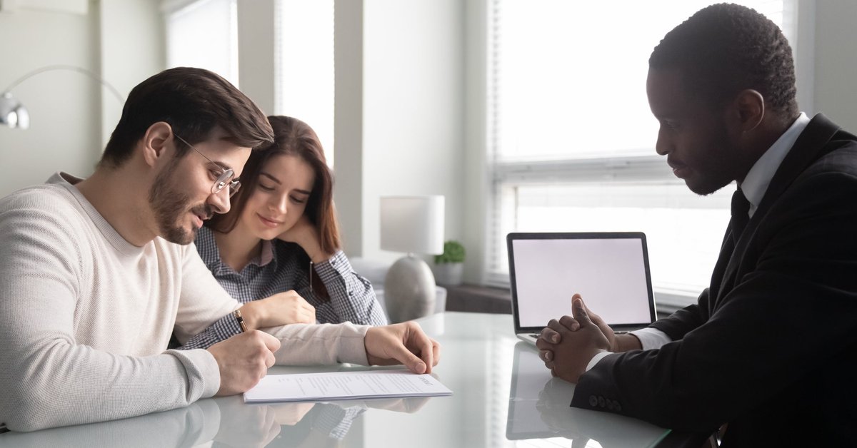 Couple signing paperwork with an agent.