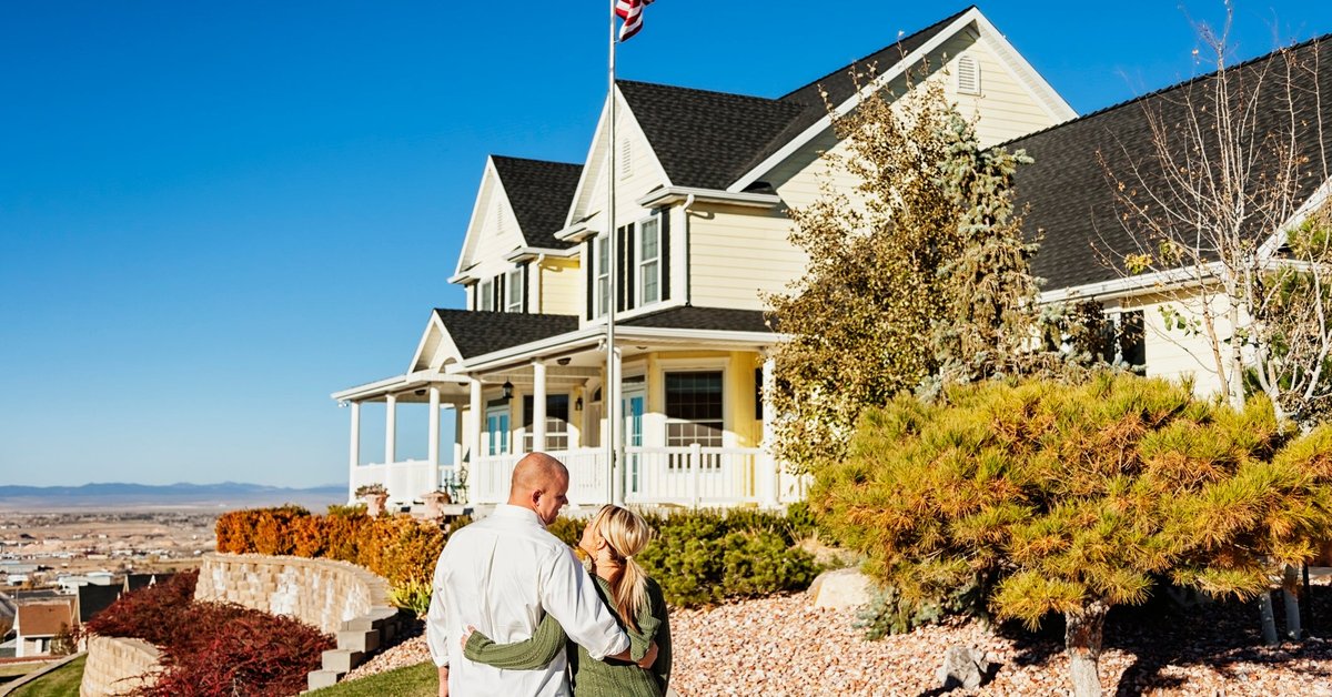 Couple standing outside admiring a large, impressive looking home.