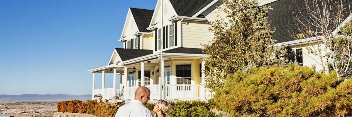 Couple standing outside admiring a large, impressive looking home.