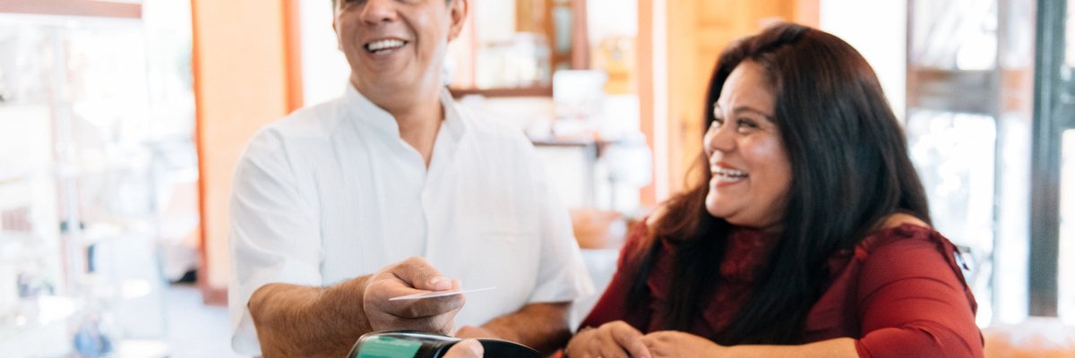 A couple check into a hotel, using a contactless credit card to pay for their stay.