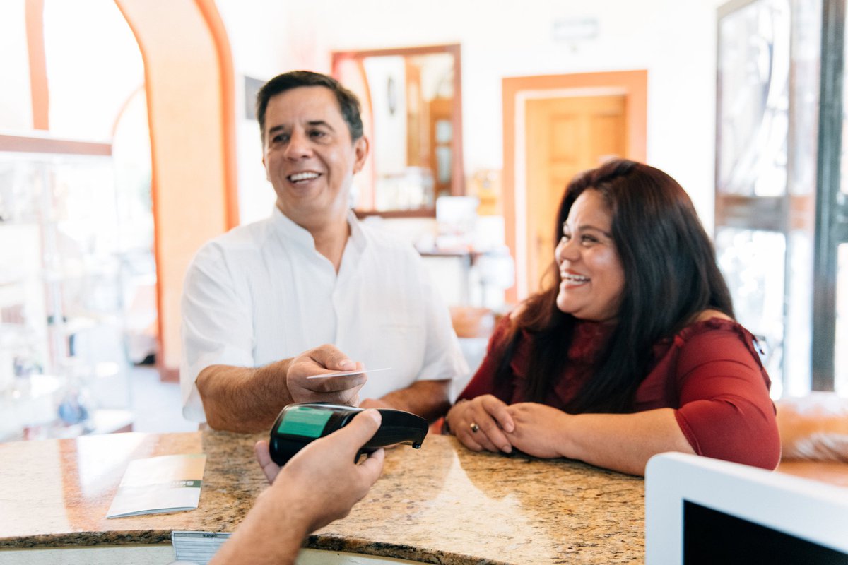 A couple check into a hotel, using a contactless credit card to pay for their stay.