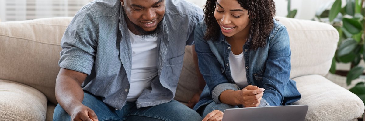 Couple using laptop and calculator together smiling.