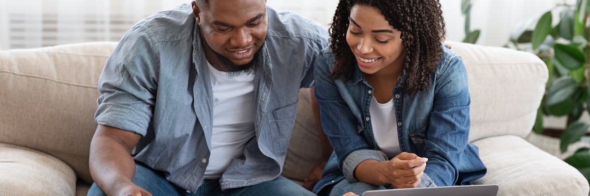 Couple using laptop and calculator together smiling.