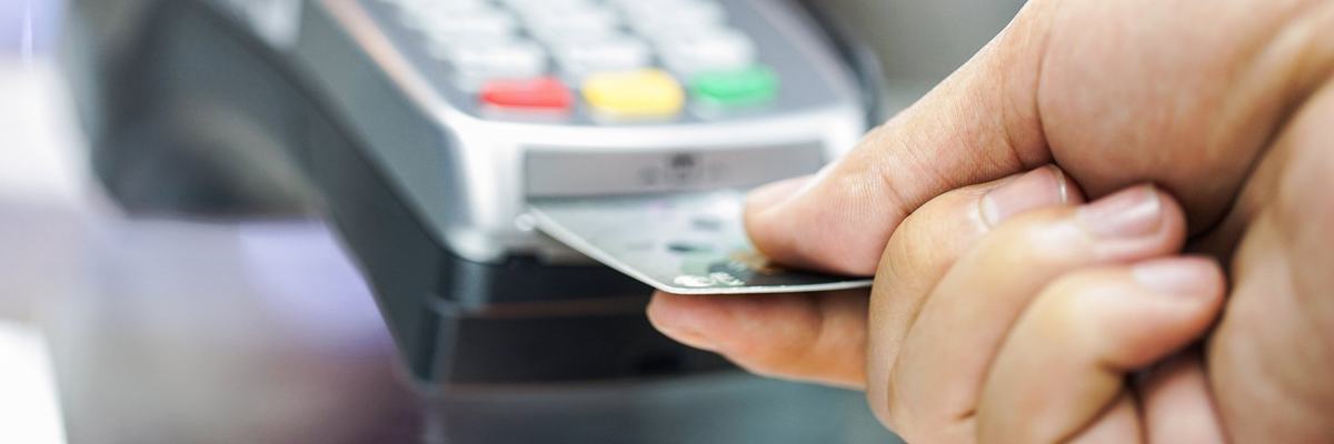A person inserting a credit card into a credit card chip reader.