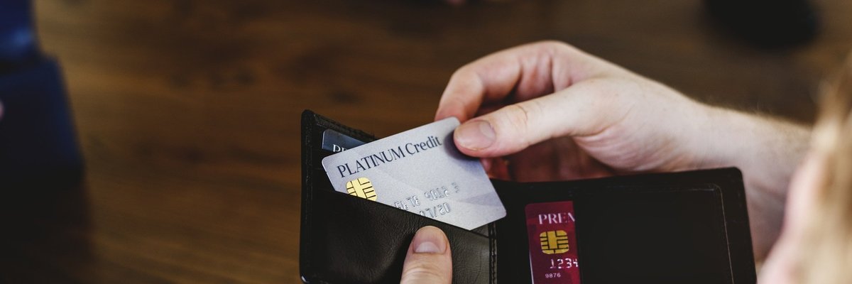 A person taking a credit card out of their wallet to pay for something.