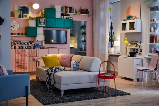 An IKEA living room setup, with pink walls and a cream sofa.
