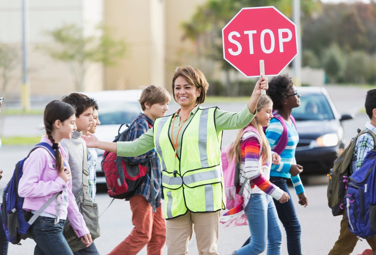 Crossing guard helping school children cross the street.