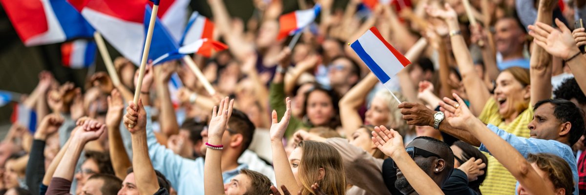 Crowd in stadium waving french flags.
