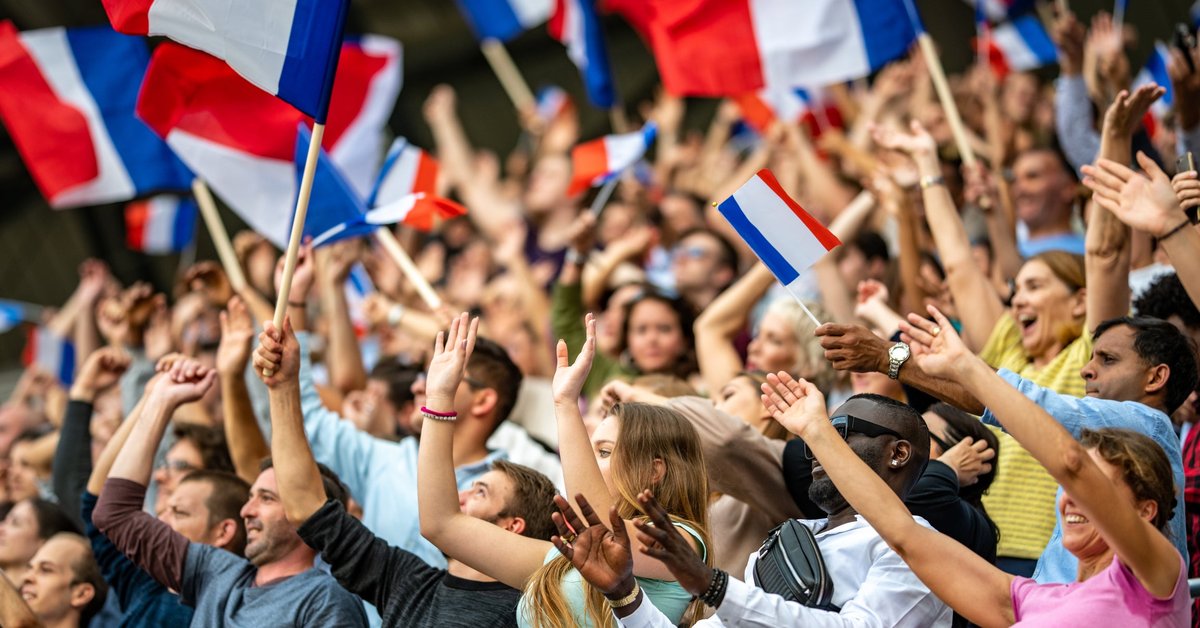 Crowd in stadium waving french flags.