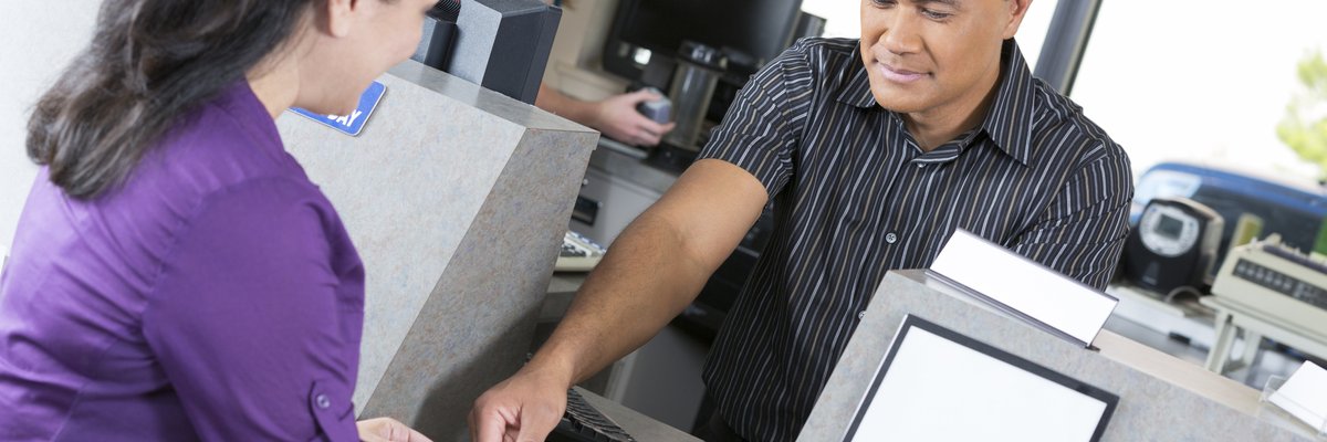 A young woman is at the bank. A teller is counting out her money.
