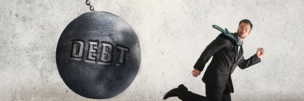 Man in suit running away from a wrecking ball that says DEBT