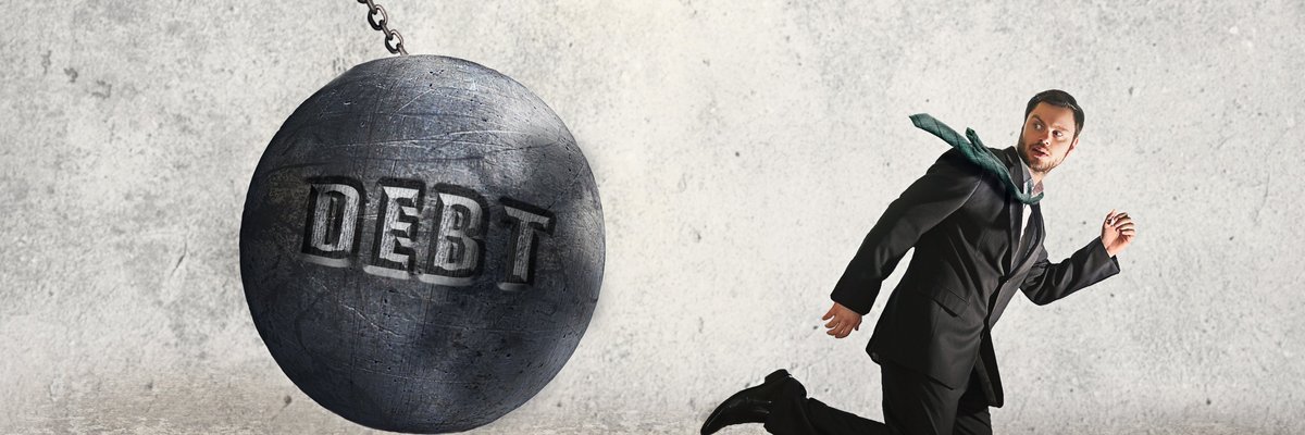 Man in suit running away from a wrecking ball that says DEBT