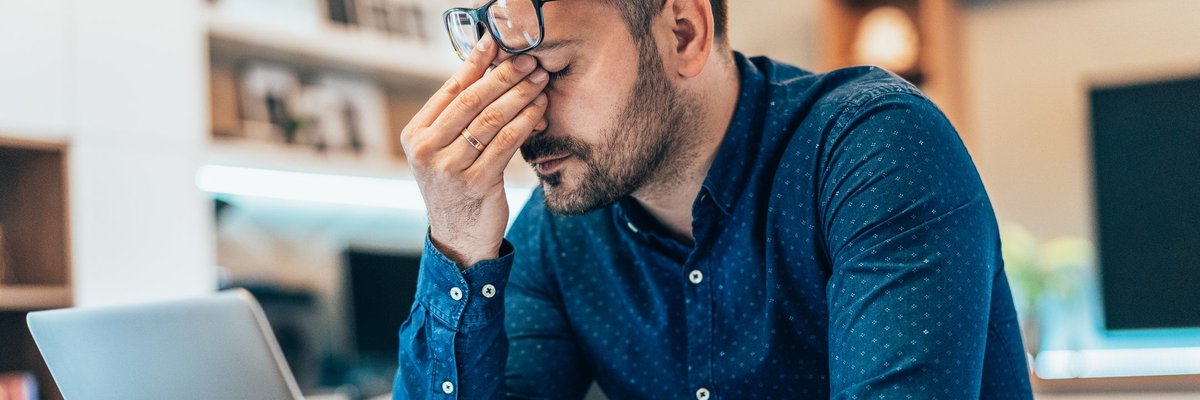 A disappointed person looking away from the computer screen and rubbing their eyes