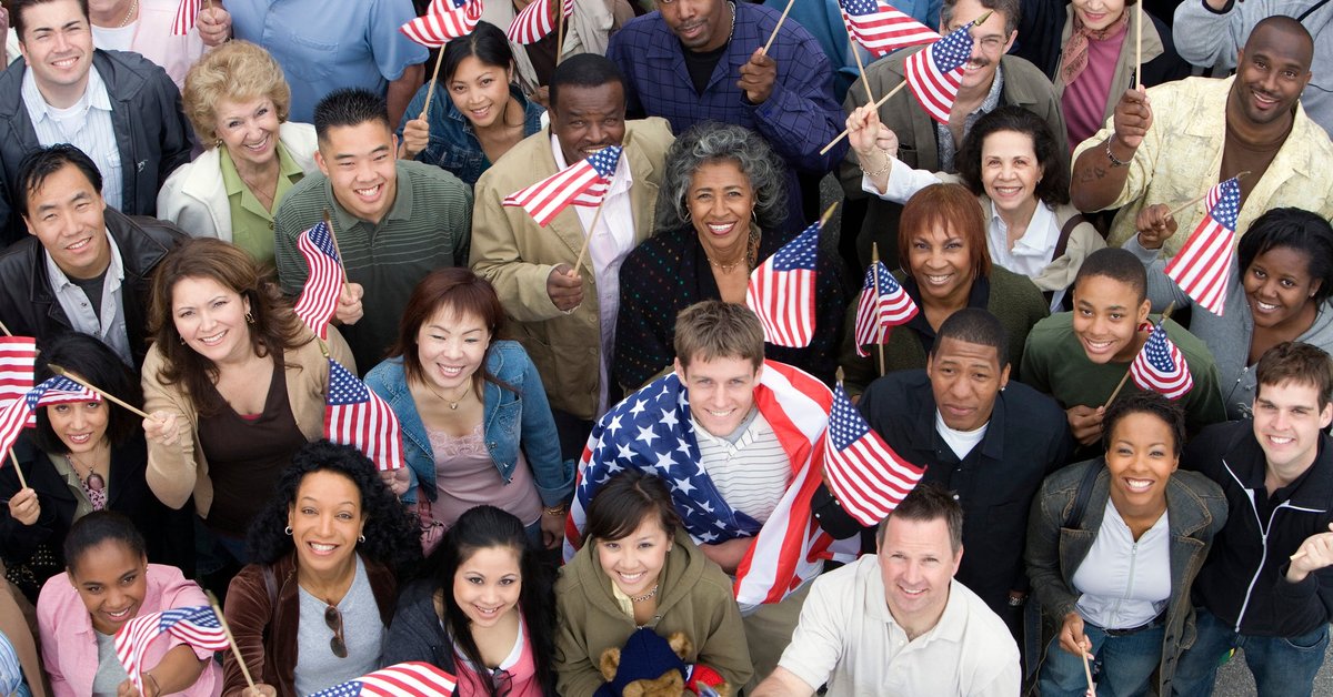Diverse crowd of people all holding American flags.