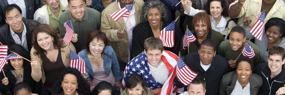 Diverse crowd of people all holding American flags.