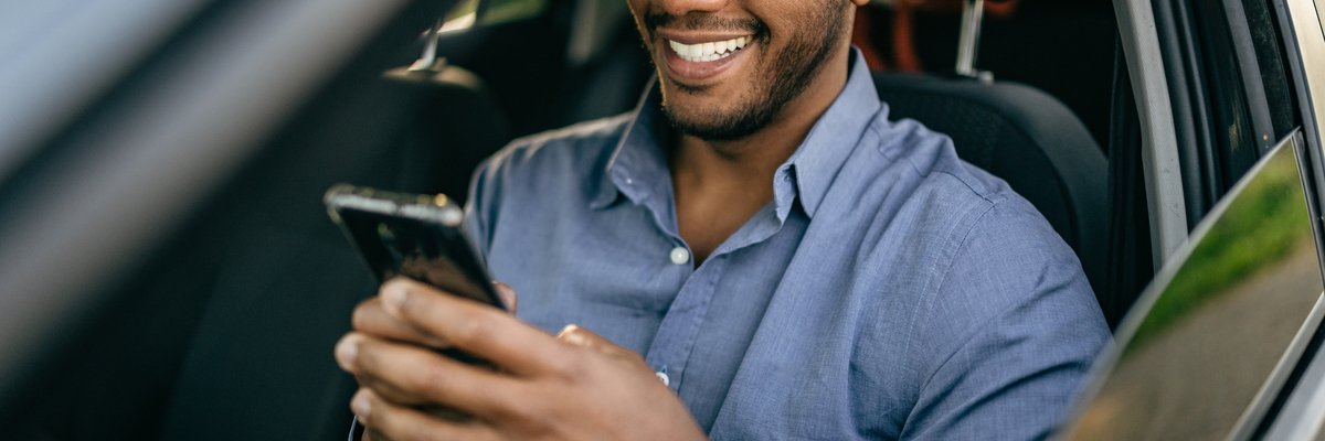 Driver sitting in driver's seat of vehicle and usince cellphone.