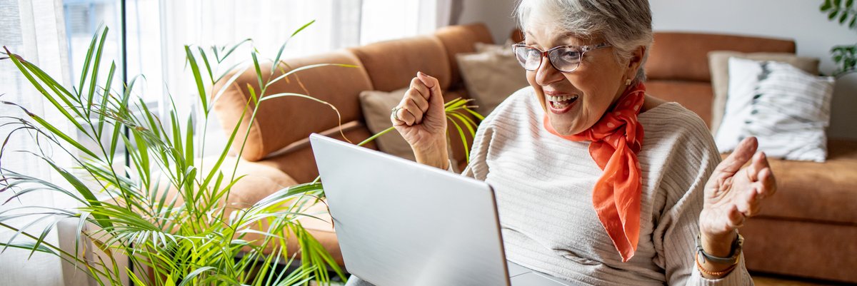 Elderly person excited about something they see on a laptop screen.