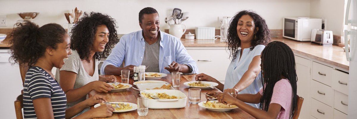 A smiling family eating breakfast together at the kitchen table.