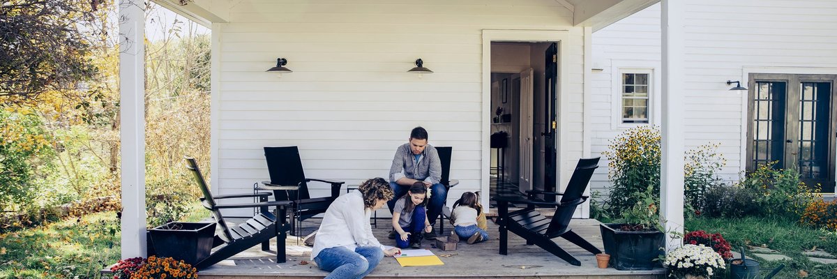 Family spending time together on the front porch of a rural home.