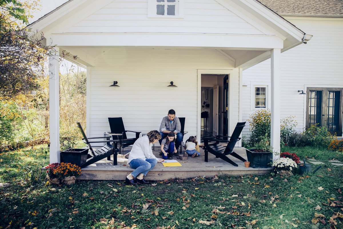 Family spending time together on the front porch of a rural home.