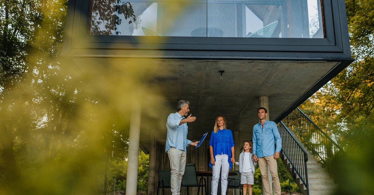 Family talking to realtor by extra modern home.
